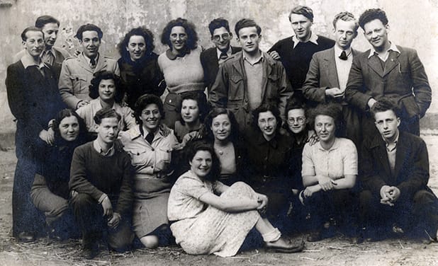Leden van de hachsjara in Utrecht, 1946.Ernst Wolf (staand, uiterst links); Albert Heymans (staand, tweede van links); Sinie Nabarro (staand, vijfde van links); Arnold (Uri) van Esso (staand, vijfde van rechts); Harry Klafter (staand, vierde van rechts); Klaus Schoenberg (staand, derde van rechts); Arie van Thijn (staand, uiterst rechts); Riwka Wolff (knielend, uiterst links); Peter Gerzon (knielend, tweede van links); Marie Leefsma (knielend, met rok, derde van links); Jettie Redner (knielend, vijfde van rechts); Leni van Esso (knielend, vierde van rechts); Tilly Bosman (knielend, tweede van rechts); Herman Heymans (knielend, uiterst rechts). Beeld: Ghetto Fighters House Archives